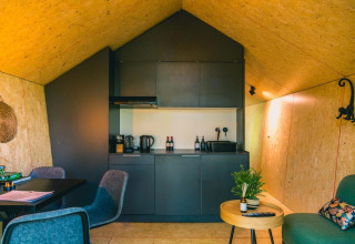 Solo Retreat lodge op de IJssel Eilanden in Nederland met een modern zwart keukentje en gezellige zithoek.