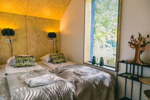 Chambre douillette avec lits jumeaux au Solo Retreat, Îles IJssel, Pays-Bas, dotée d'une grande fenêtre.