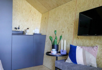 Modern lodge-interieur in Solo Retreat, IJssel Islands, met kitchenette, plant, kaarsen en wand-tv.