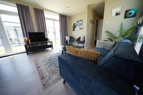Moderne woonkamer in Just Nature-lodge op de IJssel Islands, Nederland, met grote ramen en stijlvolle inrichting.