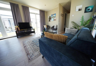 Moderne woonkamer in Just Nature-lodge op de IJssel Islands, Nederland, met grote ramen en stijlvolle inrichting.