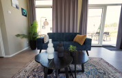 Moderne leefruimte in Just Nature lodge op de IJssel-eilanden, Nederland, met sofa, tafel en decoratie.