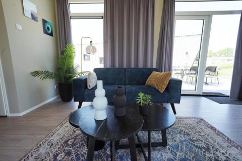 Sala moderna en Just Nature lodge en las Islas IJssel, Países Bajos, con sofá, mesa y plantas decorativas.