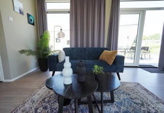 Moderne leefruimte in Just Nature lodge op de IJssel-eilanden, Nederland, met sofa, tafel en decoratie.