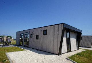 Moderne lodge bij Just Nature op de IJssel Eilanden in Nederland, onder een blauwe lucht met zitgedeelte buiten.