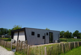 Moderne Just Nature-lodge op de IJssel Eilanden in Nederland, omheind door houten hekwerk en natuur.