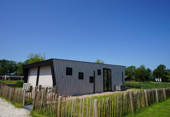 Moderne Just Nature-lodge op de IJssel Eilanden in Nederland, omheind door houten hekwerk en natuur.