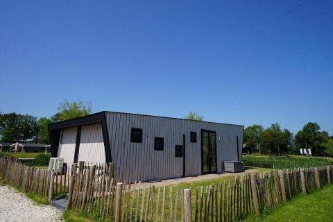 Moderne Lodge Just Nature auf den IJssel Inseln in den Niederlanden, umgeben von Natur und Zaun.