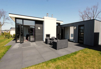 Alojamiento contemporáneo L-Cube con fachada negra y gris, grandes ventanales y terraza con muebles.