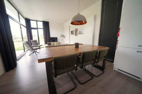 Espace salle à manger et salon moderne au lodge L-Cube à Spaarnwoude, Pays-Bas, avec grandes fenêtres.
