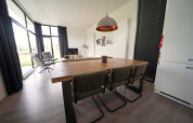 Moderne eet- en zithoek in de L-Cube lodge bij Spaarnwoude, Nederland, met grote ramen en uitzicht.