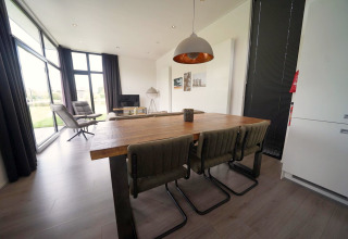 Espace salle à manger et salon moderne au lodge L-Cube à Spaarnwoude, Pays-Bas, avec grandes fenêtres.
