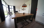 Moderne indretning af spise- og opholdsområde i L-Cube lodge ved Spaarnwoude, Holland, med store vinduer.