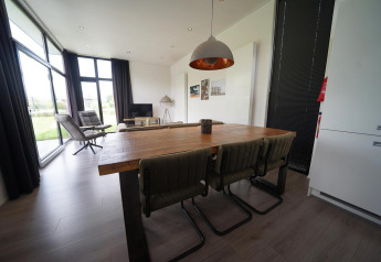 Moderne indretning af spise- og opholdsområde i L-Cube lodge ved Spaarnwoude, Holland, med store vinduer.
