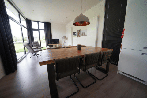 Moderne eet- en leefruimte in de L-Cube lodge te Spaarnwoude, Nederland, met grote ramen en zicht.