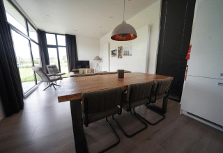 Moderne eet- en leefruimte in de L-Cube lodge te Spaarnwoude, Nederland, met grote ramen en zicht.