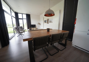 Moderne indretning af spise- og opholdsområde i L-Cube lodge ved Spaarnwoude, Holland, med store vinduer.