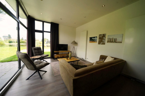 Salon moderne du L-Cube Spaarnwoude, Pays-Bas, grandes baies vitrées donnant sur jardin et lac.