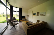 Moderne woonkamer in L-Cube Spaarnwoude, Nederland, met grote ramen en uitzicht op de tuin.