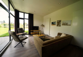 Sala moderna en la L-Cube Lodge de Spaarnwoude, Países Bajos, con ventanales y vista al jardín.