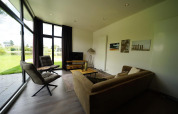 Sala moderna en la L-Cube Lodge de Spaarnwoude, Países Bajos, con ventanales y vista al jardín.