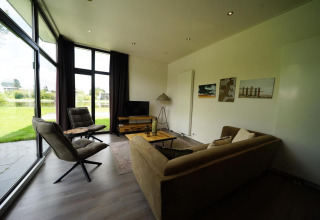 Sala moderna en la L-Cube Lodge de Spaarnwoude, Países Bajos, con ventanales y vista al jardín.