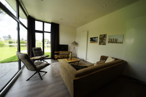 Moderne leefruimte in L-Cube Spaarnwoude, Nederland, met grote ramen en zicht op de tuin.