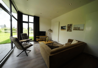 Salon moderne du L-Cube Spaarnwoude, Pays-Bas, grandes baies vitrées donnant sur jardin et lac.