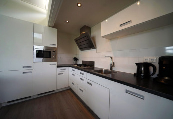 Cocina blanca moderna en la cabaña L-Cube en Spaarnwoude, Países Bajos, con electrodomésticos integrados.