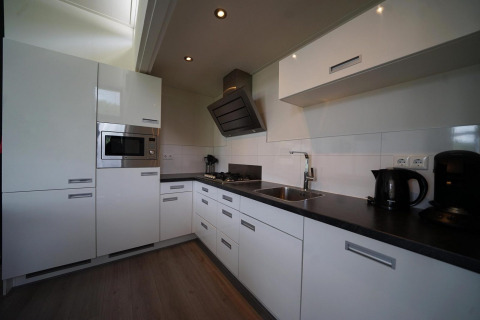 Moderne weißes L-Cube-Kücheninterieur in Spaarnwoude, Niederlande, mit integrierten Geräten.
