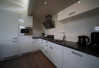 Moderne witte keuken van de L-Cube-lodge bij Spaarnwoude in Nederland met ingebouwde toestellen.