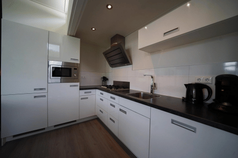 Moderne witte keuken van de L-Cube-lodge bij Spaarnwoude in Nederland met ingebouwde toestellen.