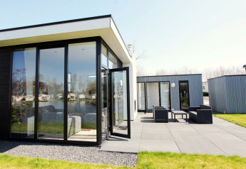Moderna cabaña L-Cube en Spaarnwoude, Países Bajos, con grandes ventanas, terraza y vista al lago.