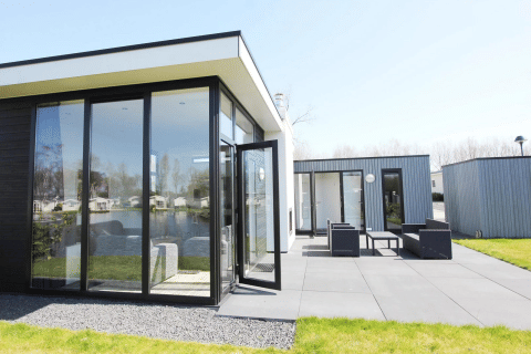 Moderno lodge L-Cube a Spaarnwoude, Paesi Bassi, con grandi finestre, patio e vista sul laghetto.