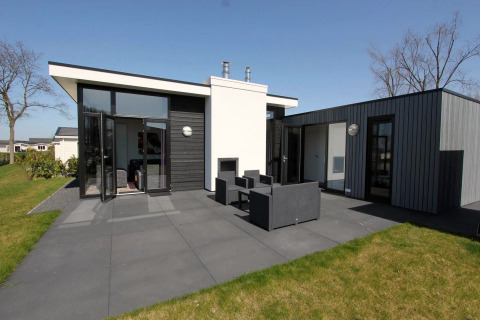 Lodge moderne L-Cube à Spaarnwoude, Pays-Bas, avec grande terrasse, mobilier de jardin et design épuré.