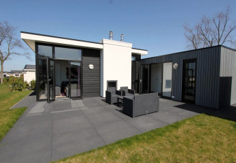 Moderna cabaña L-Cube en Spaarnwoude, Países Bajos, con terraza, muebles de exterior y diseño contemporáneo.