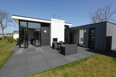 Moderna cabaña L-Cube en Spaarnwoude, Países Bajos, con terraza, muebles de exterior y diseño contemporáneo.