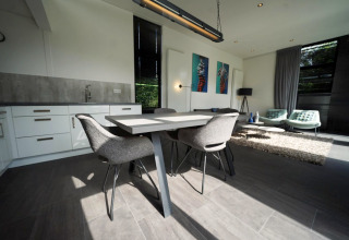 Moderne inrichting van de L-Cube lodge in Spaarnwoude, Nederland, met eettafel en zithoek in beeld.