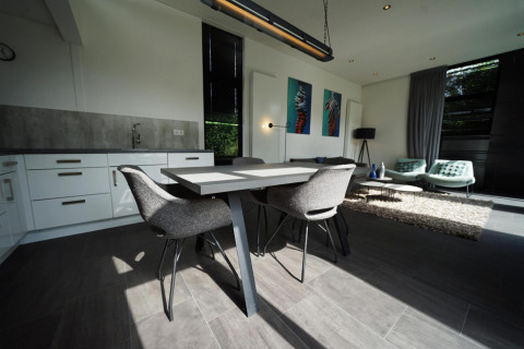 Moderne inrichting van de L-Cube lodge in Spaarnwoude, Nederland, met eettafel en zithoek in beeld.