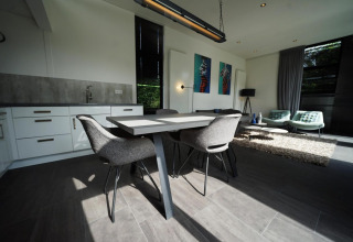 Moderne leefruimte in de L-Cube lodge te Spaarnwoude, Nederland, met eettafel en comfortabele zithoek.