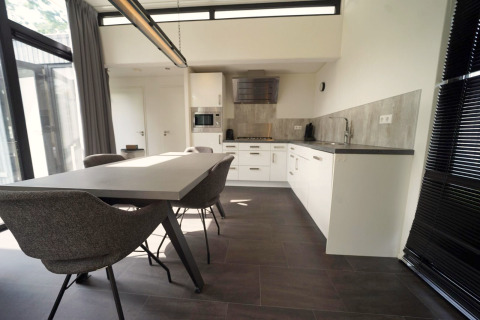 Moderne eet- en keukenruimte in L-Cube lodge te Spaarnwoude, Nederland, met stijlvol interieur en grote ramen.