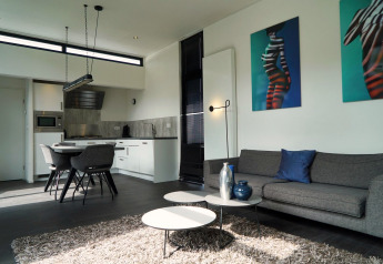 Sala de estar y cocina modernas en la L-Cube lodge en Spaarnwoude, Países Bajos, con decoración elegante y arte.