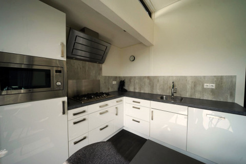 Moderne keuken in de L-Cube lodge in Spaarnwoude, Nederland, met witte kasten en grijs werkblad.