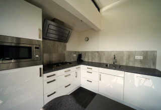 Moderne keuken in de L-Cube lodge in Spaarnwoude, Nederland, met witte kasten en grijs werkblad.