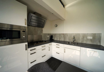 Cocina moderna en la cabaña L-Cube en Spaarnwoude, Países Bajos, con gabinetes blancos y encimera gris.