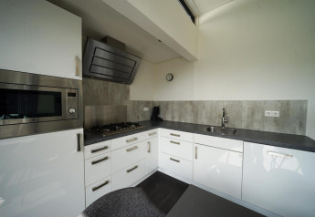 Cucina moderna nel lodge L-Cube a Spaarnwoude, Paesi Bassi, con mobili bianchi e piano grigio.