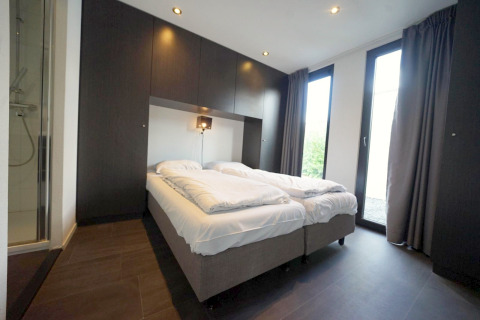 Moderne slaapkamer in L-Cube lodge Spaarnwoude, Nederland, met twee bedden en grote glazen deuren.
