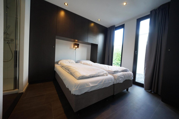 Dormitorio moderno en L-Cube lodge en Spaarnwoude, Países Bajos, con dos camas y puertas de cristal.