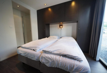 Camera moderna con letto matrimoniale, biancheria bianca e armadi scuri in L-Cube, Spaarnwoude, Paesi Bassi.