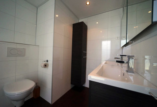 Moderne badkamer in L-Cube lodge in Spaarnwoude, Nederland, met hangtoilet en grote wastafel.